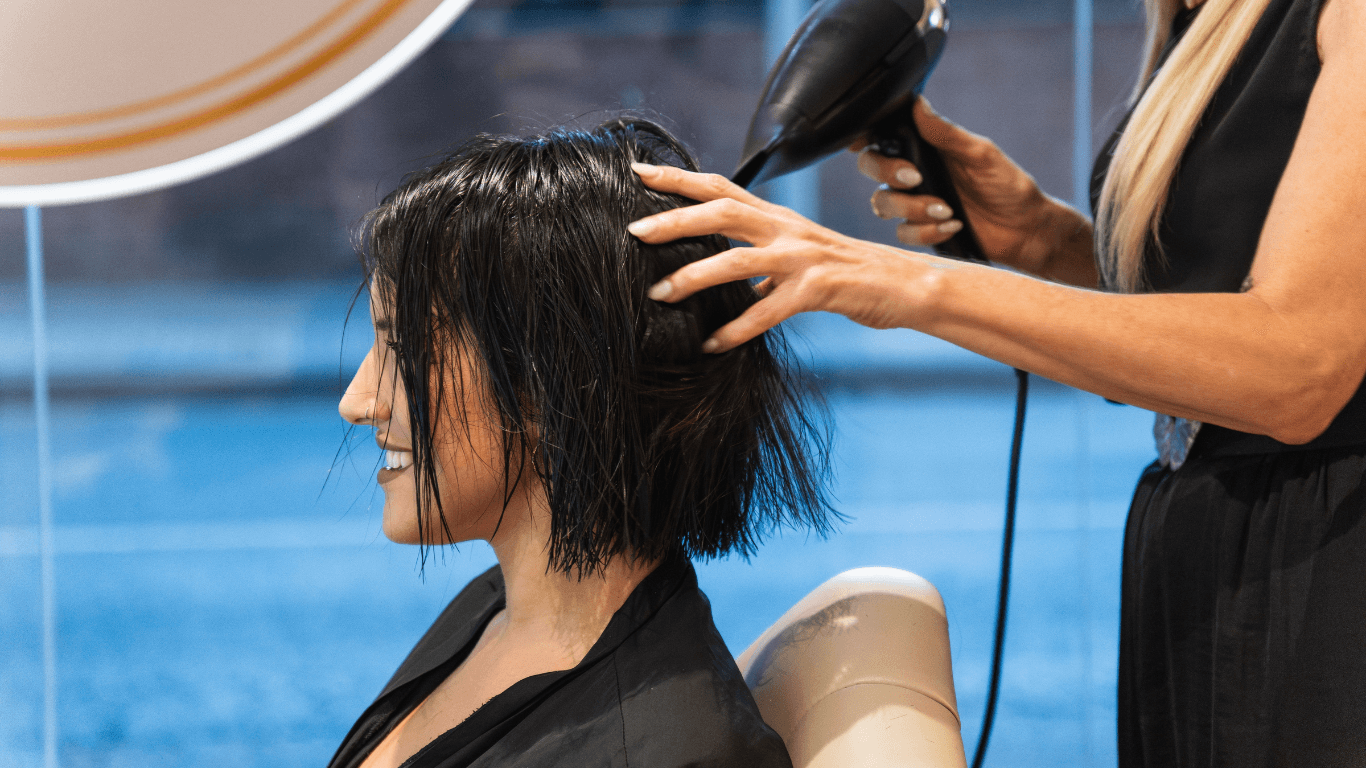 Stylist blow-drying a smiling client’s hair at Cruz Hairworks in Whitley Bay – friendly, professional salon atmosphere captured for the blog header image.