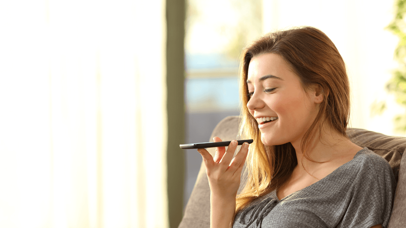Smiling woman using voice message on her phone—friendly and approachable contact image for Cruz Hairworks in Whitley Bay.