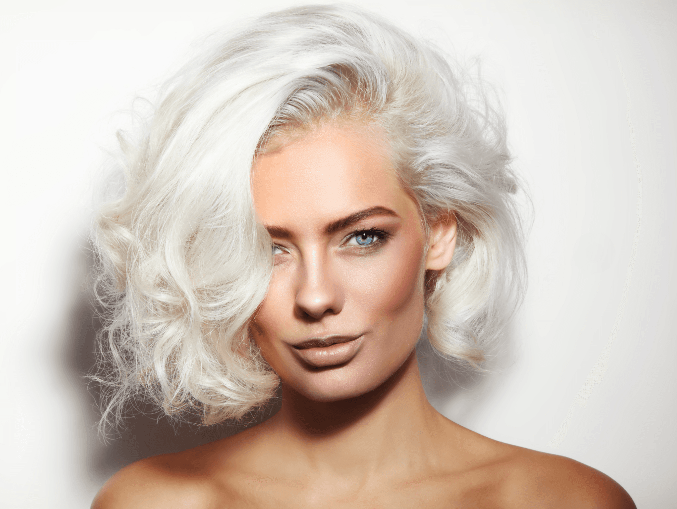 Woman with icy platinum blonde hair styled in soft waves after full head bleach treatment at Cruz Hairworks, Whitley Bay.