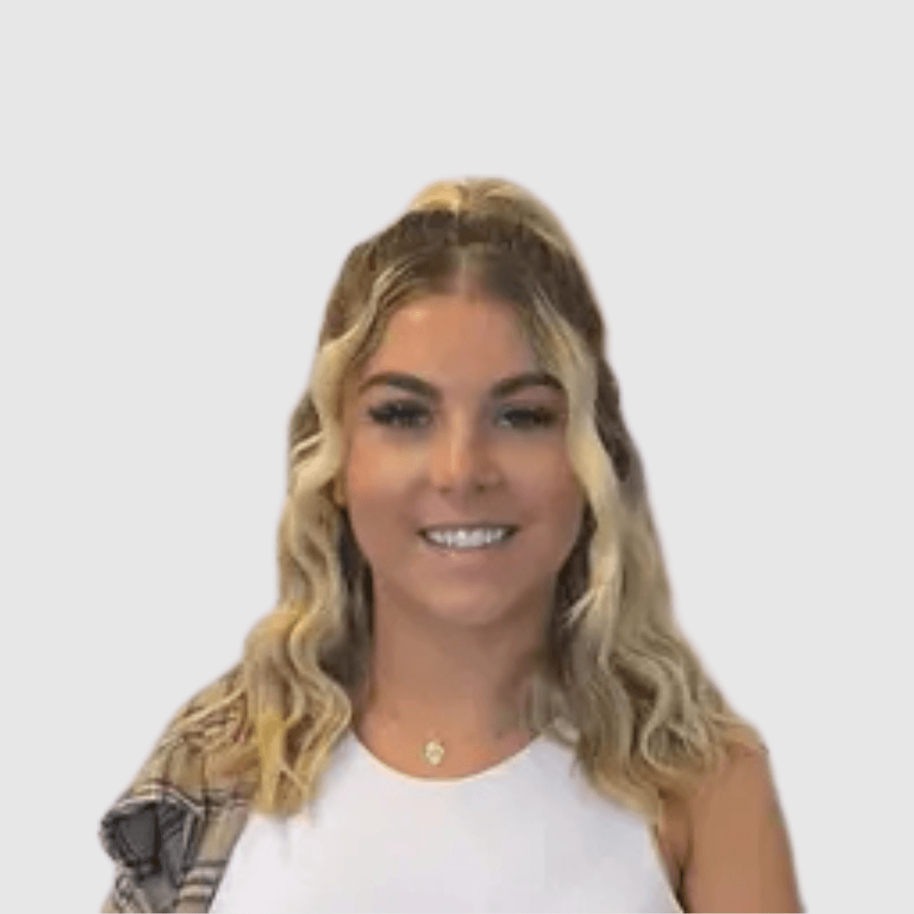 Olivia Murray, Manager & Senior Stylist at Cruz Hairworks in Whitley Bay, with wavy blonde hair and a white top, smiling at the camera.