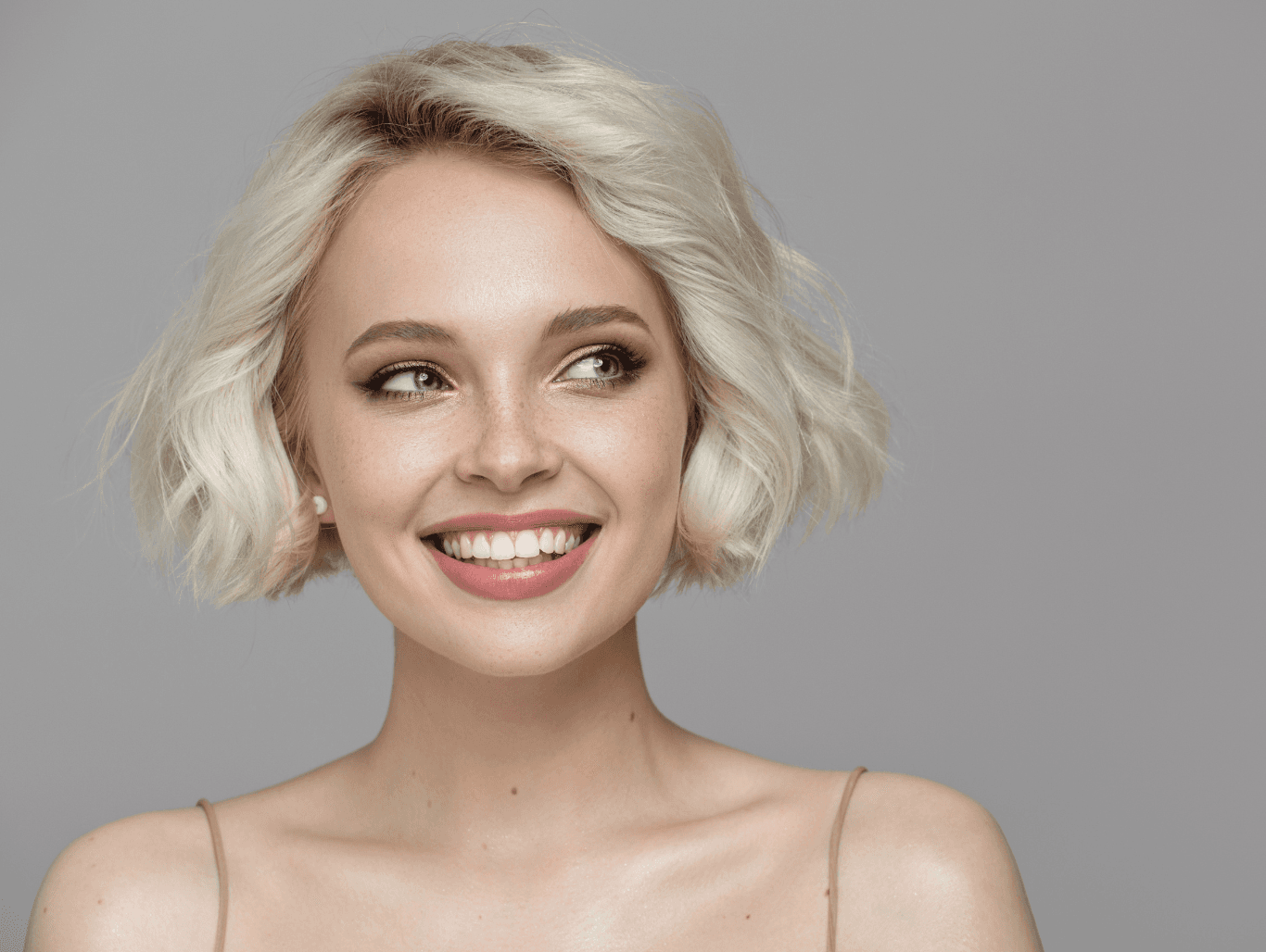 Woman with a soft, voluminous blonde bob smiling after a professional shampoo and blowdry at Cruz Hairworks
