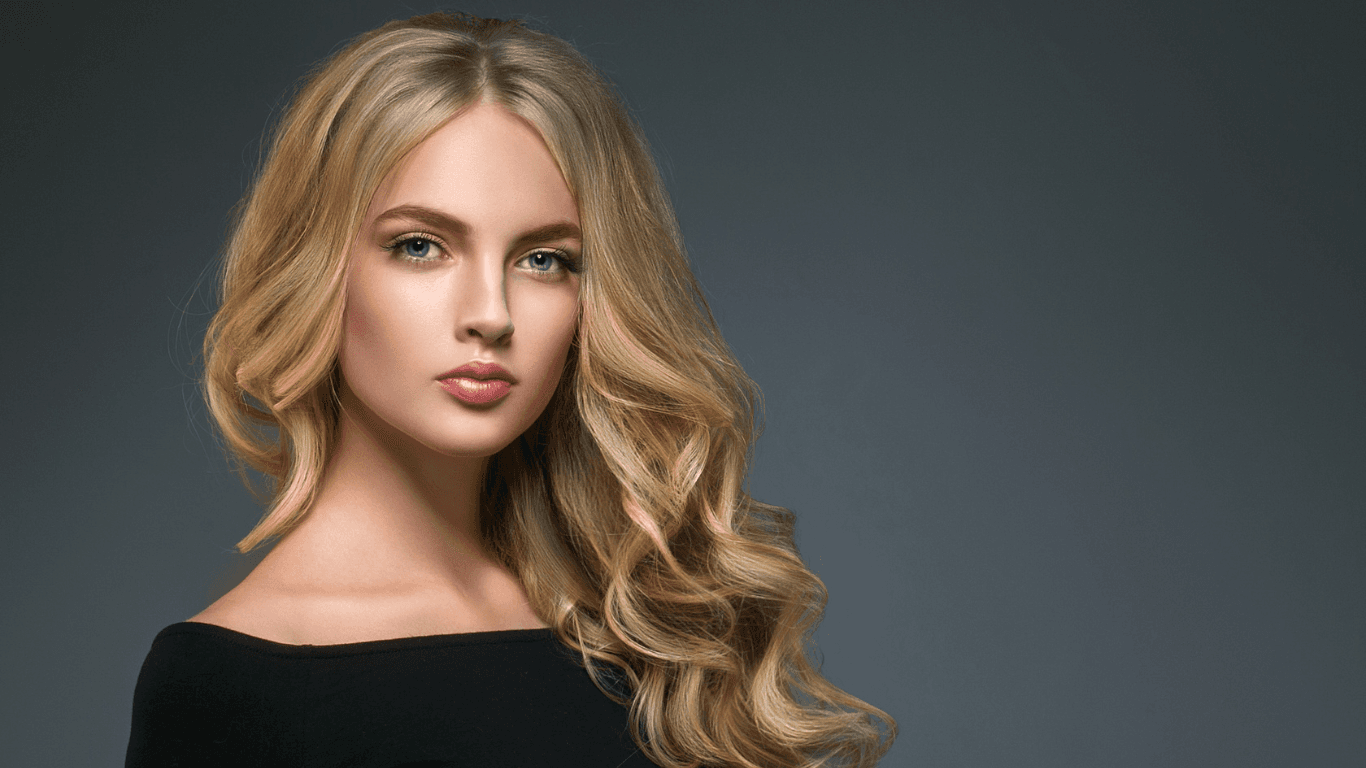Woman with soft, voluminous blonde curls after highlights – showcasing professional foil work and a polished salon finish at Cruz Hairworks in Whitley Bay.