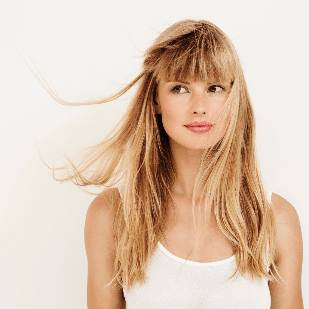 Woman with long, natural-looking blonde highlights and soft fringe – representing professional highlighting services at Cruz Hairworks in Whitley Bay.