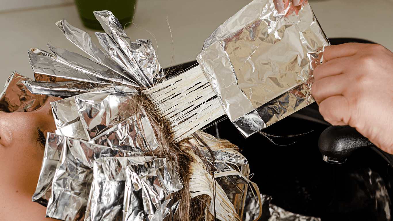 Hairdresser applying lightener with foils during a full head highlights service at Cruz Hairworks in Whitley Bay.